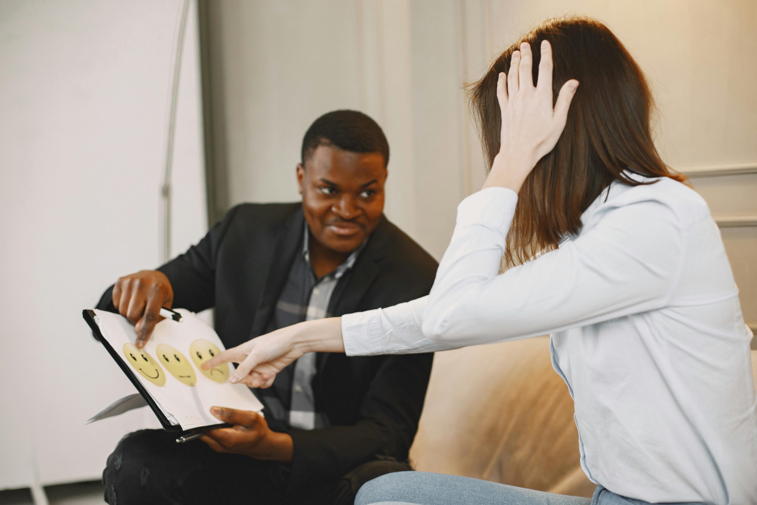 African American man and woman discussing emotions with emoji cards in a therapy session.